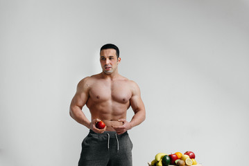 Sporty sexy guy posing on a white background with bright fruits. Diet. Healthy diet
