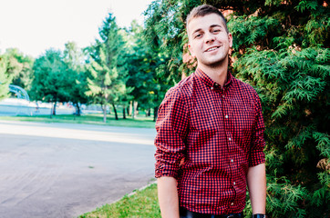 Portrait of a young guy on a background of green trees