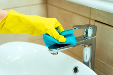 Someone is washing a sink with sponge. Someone is washing a sink in yellow gloves