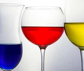 Glasses full of colored liquid of blue red and yellow
