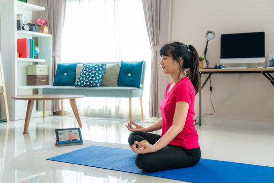 Asian Woman Making Yoga Exercise For Step Away From Their Computer To Take Mid-day Exercise Breaks Via Livestream Videos Classes On Digital Tablets During Working From Home.