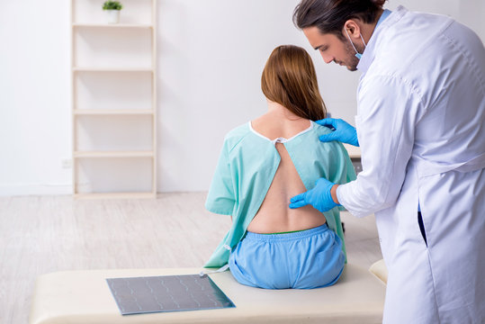 Young back injured woman visiting male doctor chiropractor