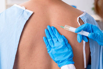 Young back injured man visiting female doctor chiropractor