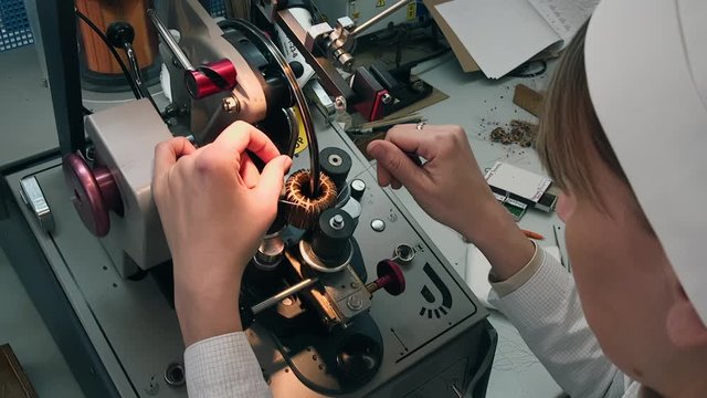 Transformer engine production modern plant Female Worker winding cooper wires on a transformer electric energy electromagnet close up
