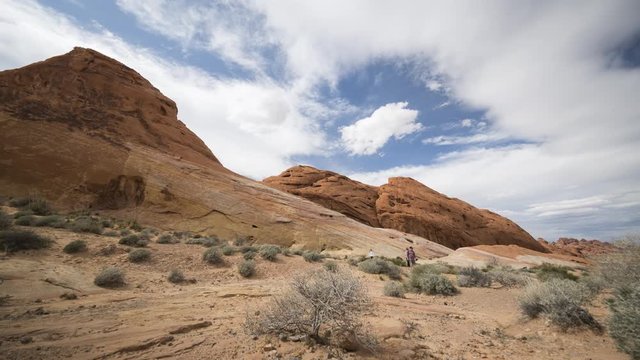An ultrawide timelapse looking past sandy areas towards a steep white dome of rock in Valley of Fire State Park in Nevada.