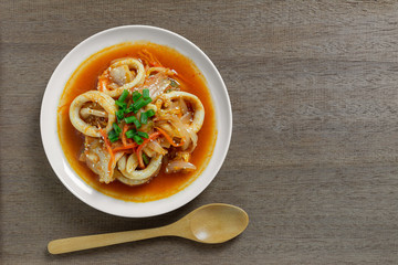 top view of stir fried squid with kimchi in a ceramic dish on wooden table. homemade style food concept.
