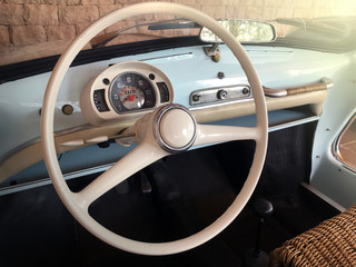 A cream colored steering wheel and robin egg blue dash of a vintage car. 
