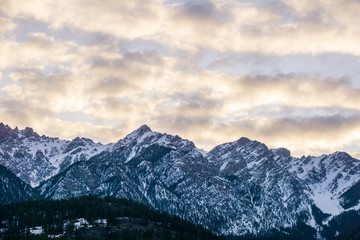 Fototapeta premium close-up view of the mountain peak with trees and snow on it sunset time.