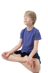 Young boy sitting practicing meditation, isolated on white background 