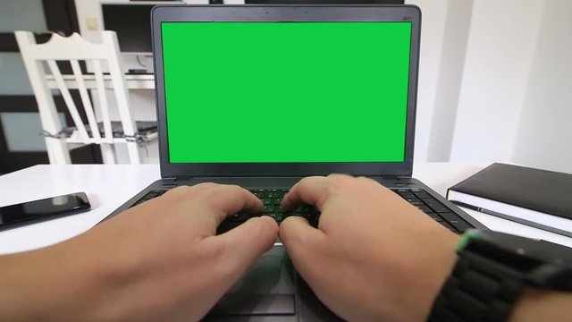 Man coding on a laptop with green screen