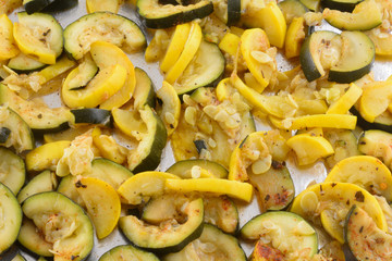 Zucchini and yellow summer crookneck squash slices on aluminum foil in baking pan sheet