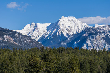 view of the mountain range with trees and snow on it sunny spring day.