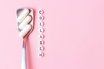 White collagen capsules lie in a teaspoon on a pink background, the inscription collagen, copy space.