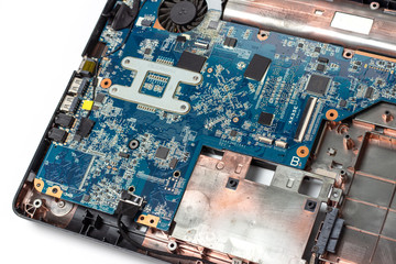 Motherboard and microcircuits on disassembled laptop close-up on white background.