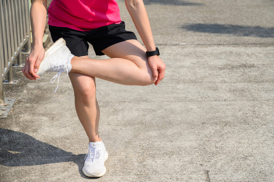 Cropped shot of runner woman do stretching to relieve tight IT Bands. The benifit of stretching can increasing flexibility performance and reduce risk of injury.