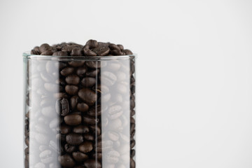 Roasted coffee beans in the clear glass jar with white background for copy text space