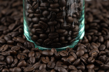 Roasted coffee beans in the clear glass jar on coffee beans background