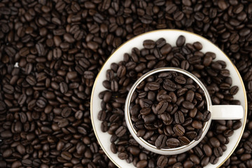 Top view of coffee cup with roasted beans on coffee beans background