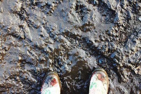 Directly Above View Of Dirty Shoes On Mud