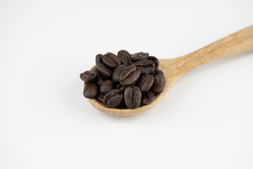 Roasted coffee beans on wooden spoon on white background