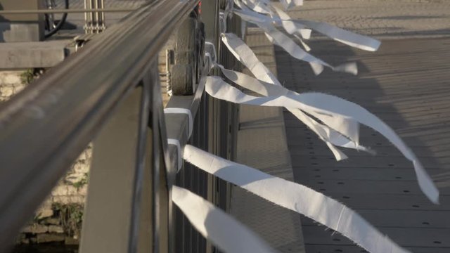 White strips of ribbon hang side by side on a handrail, slow motion