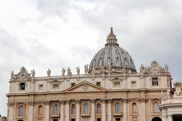 A group of Saint Statues on St. Peter's Basilica with dome and dramatic sky in Vatican City, Rome, Italy