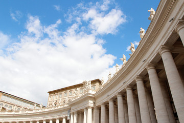 A group of Saint Statues on the colonnades of St Peter's Square with blue sky and clouds in Vatican...