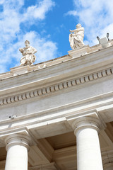 Fototapeta na wymiar Saint Statues on the colonnades of St Peter's Square with blue sky and clouds in Vatican City, Rome, Italy