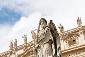Statue of St. Paul with sword in front of St Peter's Basilica with blue sky and clouds in Vatican...