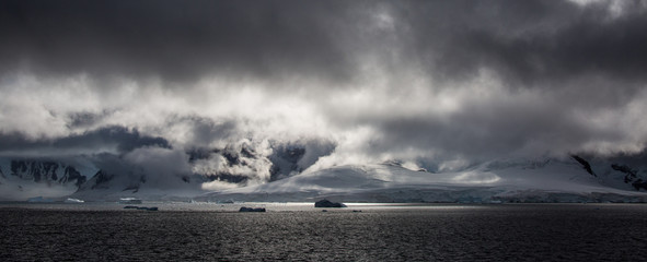 storm clouds dramaticly over the Antarctica sea and mountains with a beautiful bright reflection as a silver line on a dark sea