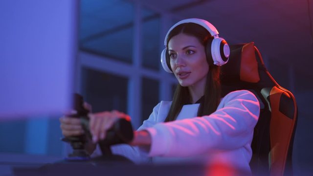 The gamer girl with headphones plays video games