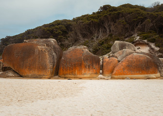 Big round rocks marked with time, orange and brown colors due to the connecting stream between the ocean and the river in Wilson's Promontory National Park, Australia