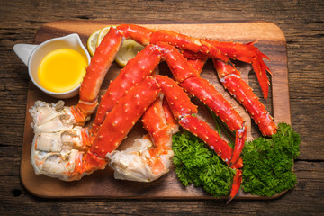 Cooked Organic Alaskan King Crab Legs with Butter and lemons, Alaskan King Crab on vintage wooden background.