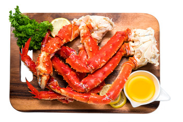 Cooked Organic Alaskan King Crab Legs with Butter and lemons, Alaskan King Crab on wood plate in white background.