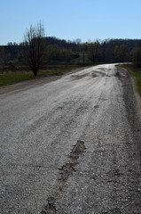 Poor condition of the road surface. Spring season. Hole in the asphalt, risk of movement by car, bad asphalt, dangerous road, potholes in asphalt.Poltava Region. Ukraine