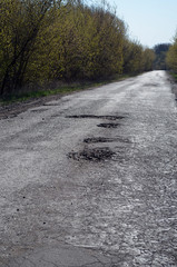 Poor condition of the road surface. Spring season. Hole in the asphalt, risk of movement by car, bad asphalt, dangerous road, potholes in asphalt.Poltava Region. Ukraine