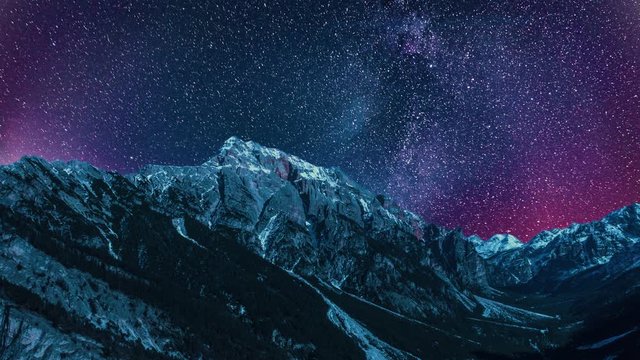 Surreal and outlandish view of the night sky above the Sella mountain in South Tyrol, Italy. Millions of bright stars on the deep violet sky, dwarfing the huge mountain beneath.