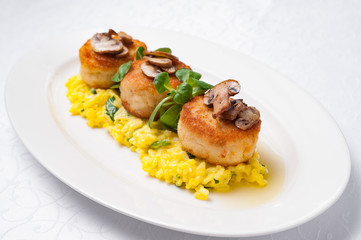 Cutlets with mushrooms on a pillow of risotto in a white plate on a white background..