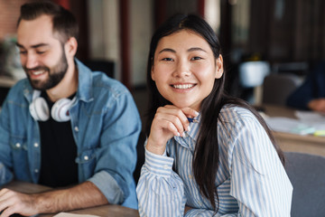Photo of multinational cheerful students smiling while studying