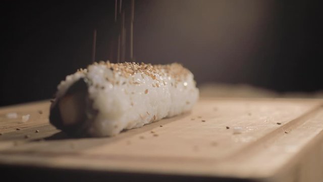 Slowmotion sesame fallo falling down on a vegan sushi maki roll.