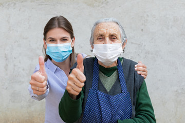 Caregiver with elderly ill woman showing thumbs up