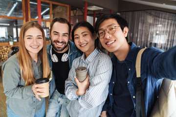 Photo of multinational cheerful students laughing while taking selfie