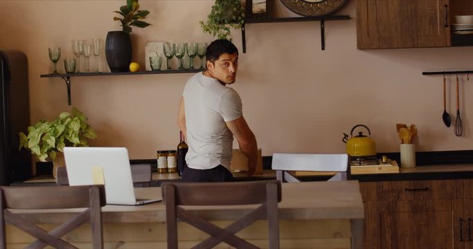 Hispanic male recieving work conference video call while cooking at home. Remote working from home, quarantine, coronavirus pandemic