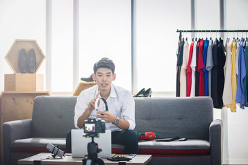 Asian man blogger broadcasting a video for selling product online such as Hats, shoes, headphones,...