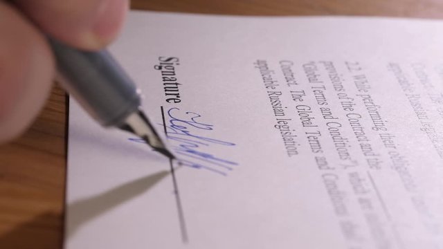 Close-up signature. The businessman signs the contract with a pen. Signing contract. Business negotiation
