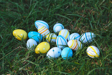 Easter eggs lay  in a yellow basket on the green grass on a sunny day. Happy easter day.