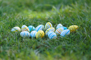 Easter eggs lay  in a yellow basket on the green grass on a sunny day. Happy easter day.