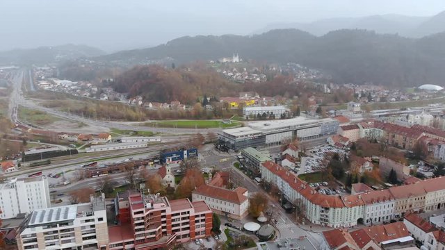 Wide angle dolly in drone shot of the beautiful city, of Celje, Jozefov Hrib/Saint Joseph's hill and the surrounding mountains during the day