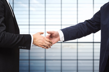 Handshake of two businessmen on the background of empty office, partnership concept, close up