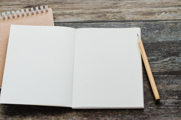 White blank notebook or plain notepd or diary or journal for writing text and message with pencil on old wood table or desk as background with copy space. Still lifestyle photo concept.
